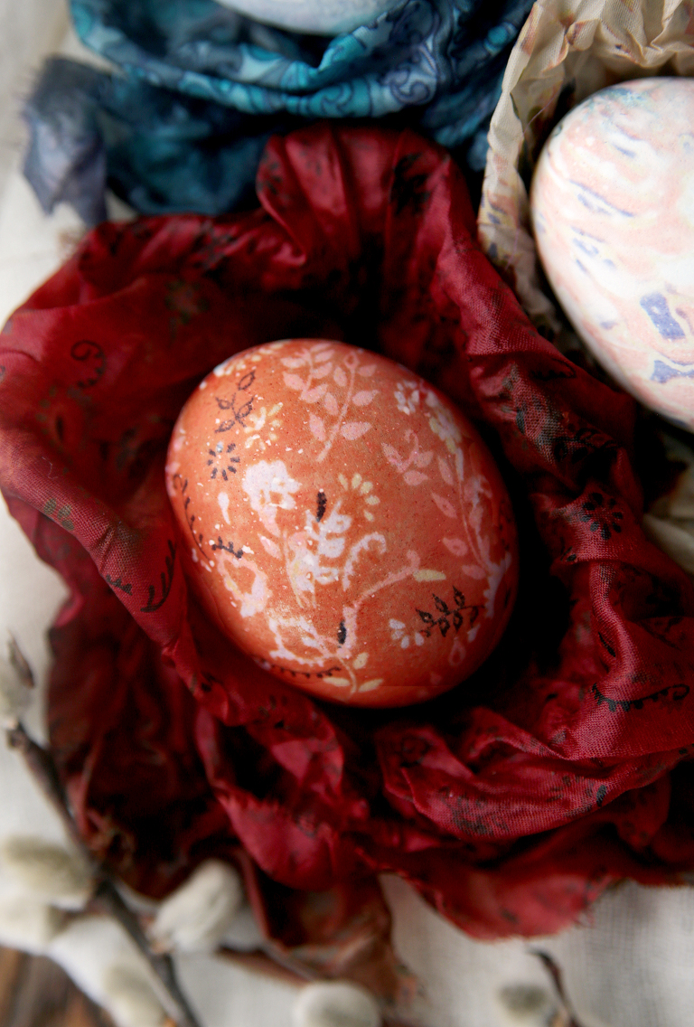 red floral silk dyed Easter egg sitting on piece of red silk fabric