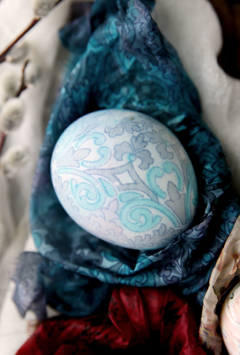 blue paisley silk dyed egg sitting on piece of silk fabric