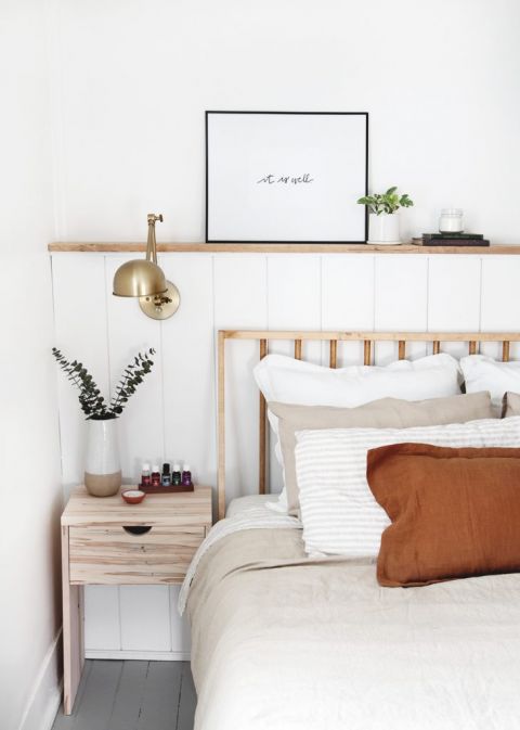 shiplap wall with brass lamp on it next to modern wood bed