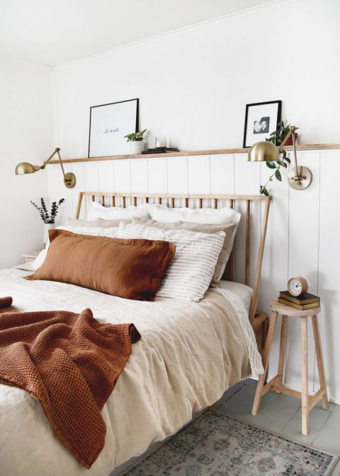 modern bed with rust blanket and brass lamp on shiplap wall