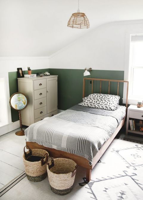 wood bed in kids room with half painted green wall