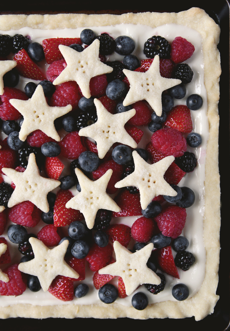 close up of lemon berry tart with fresh fruit on it and topped with shortbread cookie stars