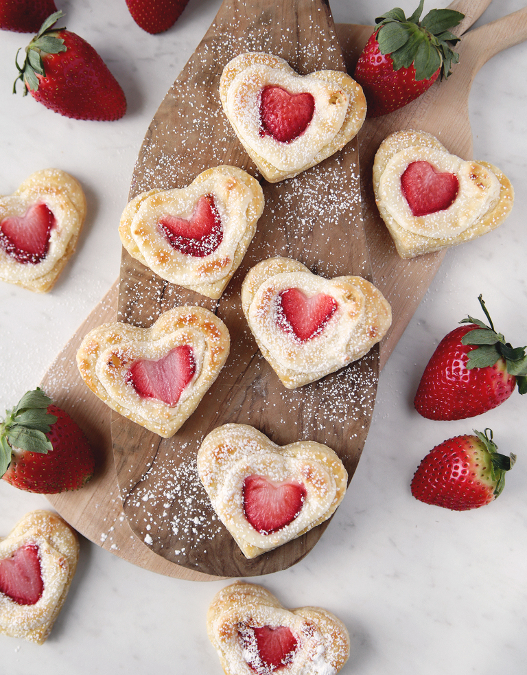 wood cutting boards with strawberry cream cheese heart danishes on them and strawberries around them