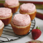 close up of strawberry rhubarb cupcake with strawberry next to cupcake