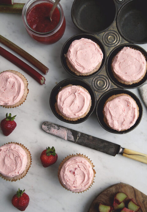 overhead shot of frosted strawberry cupcakes with butter pocketknife laying next to cupcakes