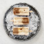 three caramel cold brew coffee popsicles on ice in pie plate