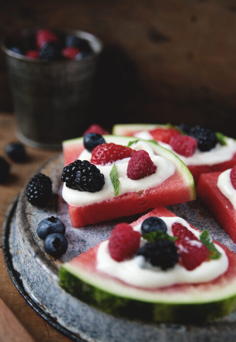 slice of watermelon fruit pizza on metal pie plates with berries on it